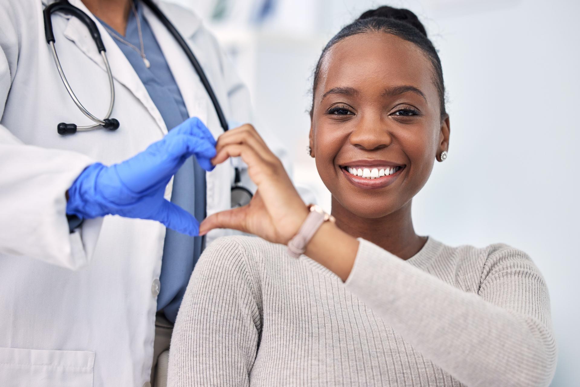 Mulher negra, paciente e médica com sorriso, consulta e emoji de coração para cardio saúde, check-up e consulta. Felicidade, apoio e bem-estar para medicina, saúde e exame físico