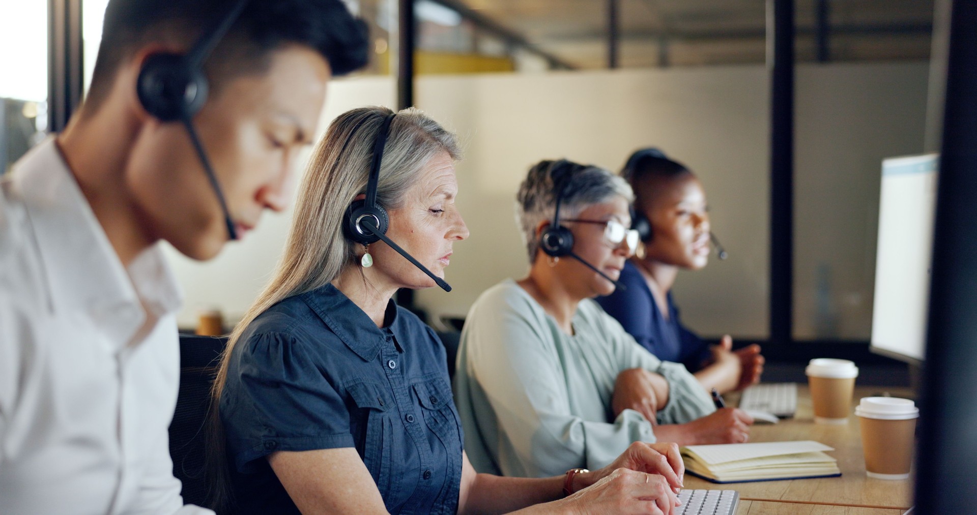 Consultora de call center sênior, mulher e fale conosco, CRM e conversando no atendimento ao cliente, computador na mesa. Chamada telefônica, telemarketing e diversidade, escrita em notebook no espaço de coworking e fone de ouvido